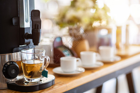 早晨关闭咖啡机的茶叶和酒店餐桌装饰品上的咖啡杯以及子拿铁图片