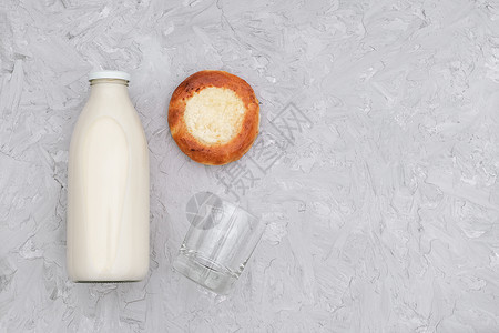 玻璃瓶装牛奶一个空玻璃杯灰色背景上新鲜出炉的小圆面包带复制空间钙蔬菜小吃图片