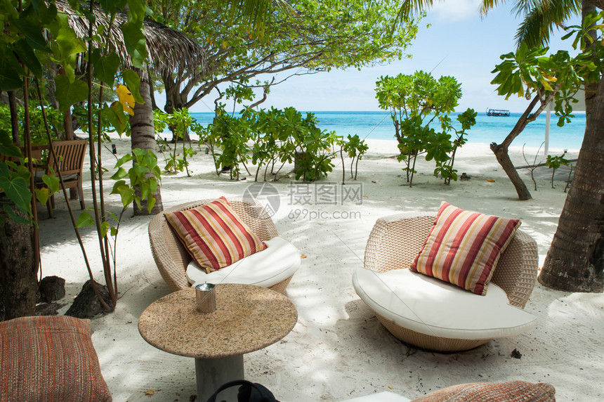 两张椅子上面有豪华的窗帘和桌椅供游客在前头的桌垫松绿海与棕榈树相距遥远的地方白沙子桌博拉立方体图片