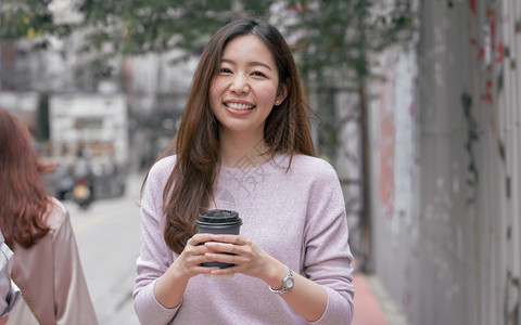 亚洲美丽的女在冬季走街边喝咖啡时饮的亚洲美丽女种族的微笑复制空间图片