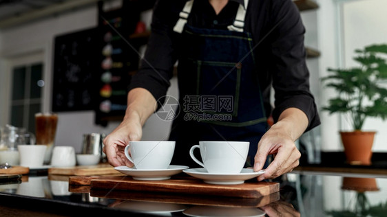 泰国咖啡店制造商手持机上的有选择焦点白咖啡杯马克奶油子图片