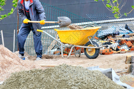 黄色建筑手推车中背着一把铲子装载沙的黄色建筑手推车工人用铲子背景