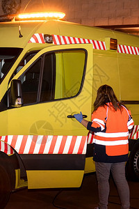 一名面目全非的救护车女司机在工作中准备协助紧急情况的夜景一名面目全非的救护车女司机在工作中准备协助紧急情况的夜景快速地面包车运输图片