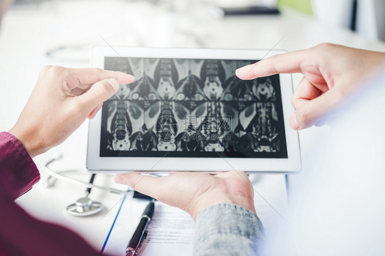 医生咨询病人在数字平板电脑片上提交结果X光片的病人关于问题的医生咨询骨移植药物图片