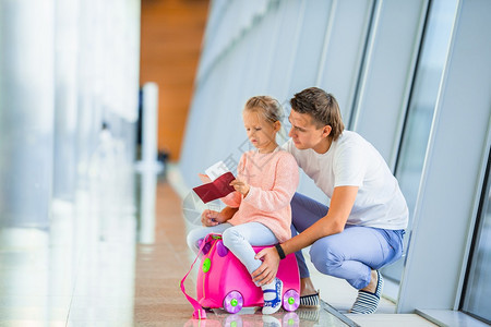 女孩们航班在国际机场快乐的家庭父亲和小女孩在国际机场快乐家庭与两个孩子在机场快乐家庭玩得开心等待登机假期图片