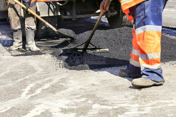 建造工作场所公路人小组利用平板和木制层新鲜热沥青更了道路的一段并用块铲子和木制层对面平衡地在上分配工作组以人操的方式将热沥青与铁图片