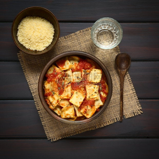塞满乡村用土制番茄酱在生锈碗里烤焦拉维奥和土自制番茄酱用小碗杯水和侧边木勺子加奶酪用自然光照黑木头图片