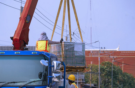 货物反光的重两名工人正在向公路建筑工地转移许多混凝土砖地板这些水泥砖铺在蓬隆卡车上图片