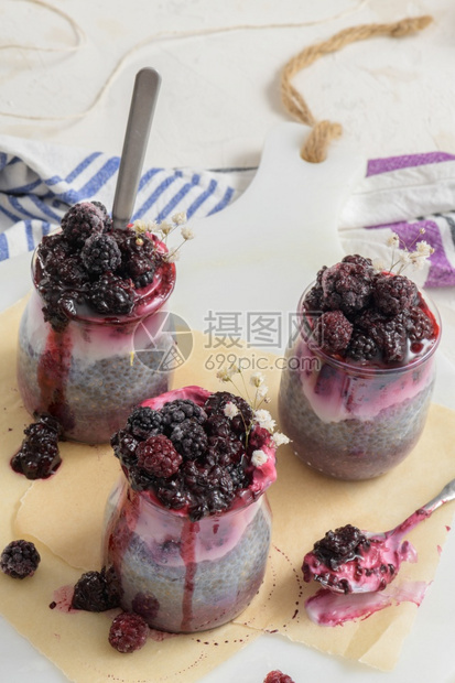 加黑莓的Chia布丁在白桌上的玻璃罐中三块种子生的牛奶图片