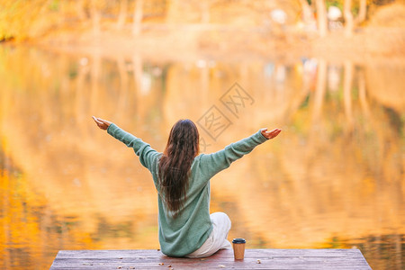 十月秋天公园的美丽女子张开双臂享受温暖的天气秋日概念公园的咖啡美女积极图片