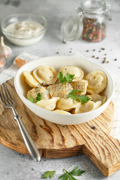 俄语叉食谱肉片Russianppemeni在木制供餐板上的白配有肉罗维奥利菜图片