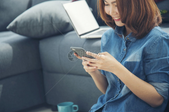 聪明的女孩专业微笑面对亚洲女手持智能机与电子商务购物在线网站阅读文章博客视频年轻女手持电话技术生活方式女使用智能手机图片