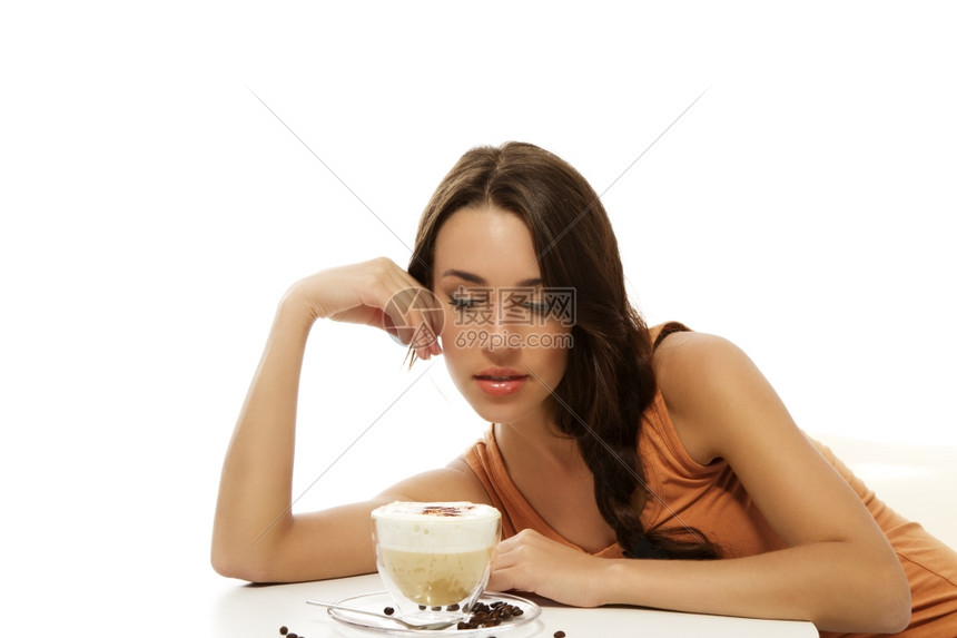 淑女拿铁美丽的人看着她面前的卡布奇诺咖啡在桌子上美丽的女人看着她面前的卡布奇诺咖啡在白色背景的桌子上女孩图片