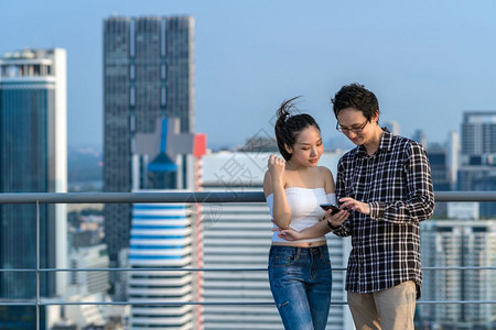 英俊的女朋友吃惊同业商人和穿便衣妇女正在商业中心的市大楼屋顶上使用智能手机利他们的业务实现概念成就在商业中心城市图片