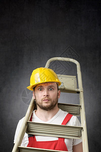 笨的建筑工人站在梯子上着一个像手持梯子的笨工人一样黄色的维护事故图片