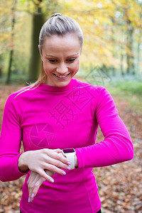 跑步女在秋季林地露天表演在智能观察下寻找活动追踪器跑训练图片