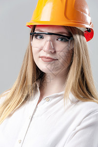模型承包商建造一位有魅力的年轻女子肖像金发戴橙色头盔和眼镜印在中灰背面的色玻璃上一位有吸引力的年轻女子肖像金色头发印在橙盔上的中图片