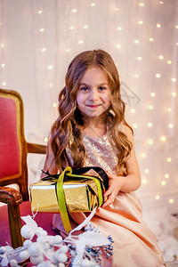 窗户包装好的室内可爱卷发小女孩在圣诞节前夕新年快乐的情绪期待惊喜在圣诞节前夕带着礼物的卷发可爱小女孩在新年前图片