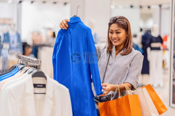 购物者中央快乐的亚洲妇女在玻璃店商选择服装在部门中心购物和狂生活方式休闲销售和黑色星期五概念中采取快乐行动欢的亚洲妇女顾客图片