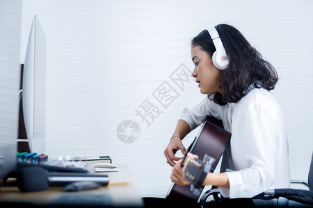 生产人们唱歌专业音乐家亚洲女青年发声员佩戴耳机弹吉他在家庭数字工作室录音一首歌乐制作技术概念笑声图片