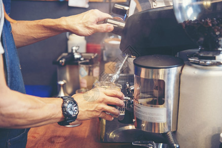 机器制服茶在意大利咖啡店厅里加牛奶的咖啡杯Cappuccucino紧握着咖啡馆的手机为客户自助餐厅制作棕色拿铁艺术背景图片