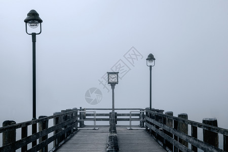 雄伟德国Konigsee湖边两个灯柱和旧时钟的雾中孤独木头码的景象谷邮政图片