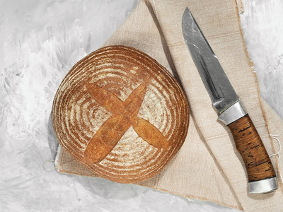 法国面包粮食美它位于灰色背景上紧靠棉纸巾和刀子的边上Name图片