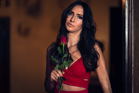 时髦的礼物一个美丽优雅的女人肖像穿着红色晚礼服拿着玫瑰周年纪念日图片