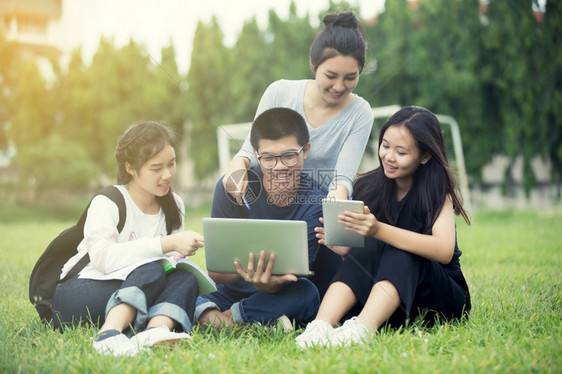 坐在草坪上一起学习的学生团体图片