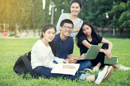 坐在草坪上学习的学生团体照片图片