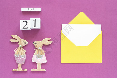 礼物或者日历4月21日一对木制复活节兔子黄色信封紫纸背景上有空白卡概念天主教复活节样机模板用于刻字文本或您的设计顶视图卡片图片
