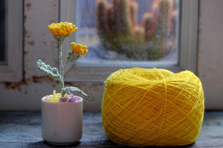 木桌上的编织花与黄色毛线球图片