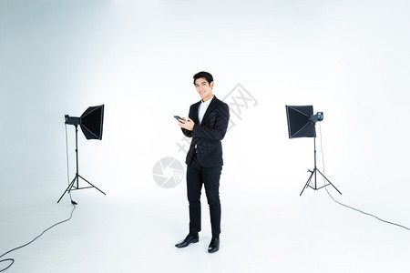 时尚英俊的亚洲年轻帅哥在智能手机打字信息中被孤立在白色灰空复制间演播室里的人在幕后显示灯光背景室内摄影棚拍吸引人的亚洲沟通图片