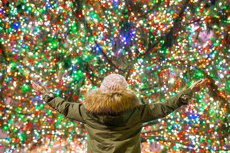 纽约洛克菲勒圣诞树背景上的快乐女孩洛克菲勒中心美丽的圣诞树纽约洛克菲勒圣诞树背景上的快乐女孩联合现代丰富多彩图片