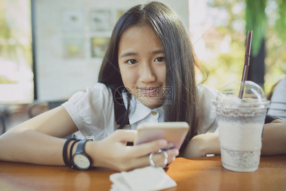 韩国人带着智能手机微笑的面容和手持智能电话紧地面对着亚洲青少年的幸福美丽迷人图片