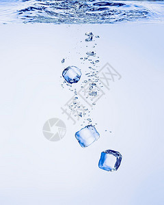 蓝色的冻结寒冷冰立方体在清澈水中坠落有泡图片