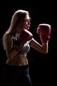 健身和拳击期间的女孩戴着拳击手套的女人穿着运动服灰色布的感战斗机女孩魅力黑色的竞争图片