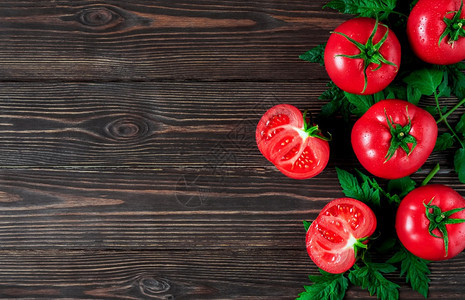 午餐关心整块新的全西红柿和半切的西红柿在深木背景上安排在水滴子中用红番茄做黑木底布局用于文字布局意大利语图片