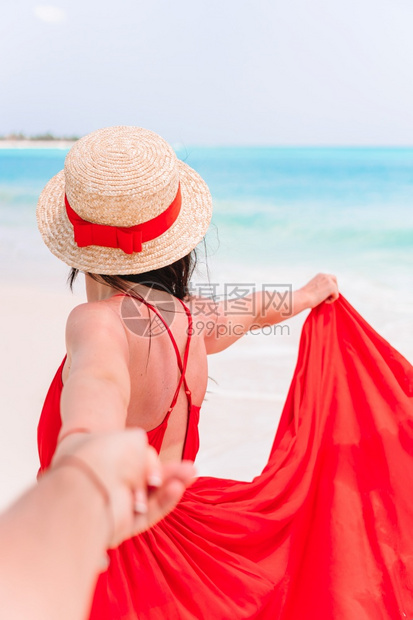比基尼穿着美丽的红礼服和草帽年轻女孩跟着我的概念穿美丽红礼服女孩在海面背景下年轻的女孩在海面上快乐的目地图片
