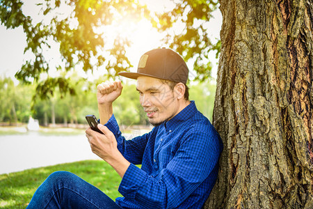 现代的成人蓝衬衫使用智能手机上网各地的科技社交媒体及自然背景阳光在网络上使用智能手机蓝色的图片