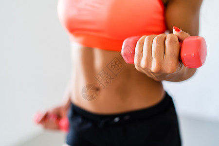 强的在训练锻炼时用哑铃做比塞普卷子的运动健壮女员在训练锻炼时有氧运动姿势与白种背景隔离的肌肉女卷曲图片