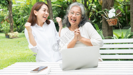 退休后学习技术概念和老年人适应改造亚洲女儿教育年长妇使用计算机笔记本电脑手提在线社交媒体教授年长老妇女的亚洲儿护士快乐的幸福图片
