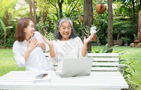 简单的个人电脑快乐退休后学习技术概念和老年人适应改造亚洲女儿教育年长妇使用计算机笔记本电脑手提在线社交媒体教授年长老妇女的亚洲儿图片