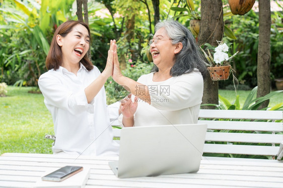 退休后学习技术概念和老年人适应改造亚洲女儿教育年长妇使用计算机笔记本电脑手提在线社交媒体教授年长老妇女的亚洲儿在线快乐年长图片