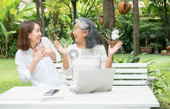 健康退休人员后学习技术概念和老年人适应改造亚洲女儿教育年长妇使用计算机笔记本电脑手提在线社交媒体教授年长老妇女的亚洲儿愉快图片