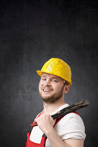 难的工业技术员快乐笑着的水管工用一个铁扳手微笑的水工一个快乐的笑着水管工肖像图片