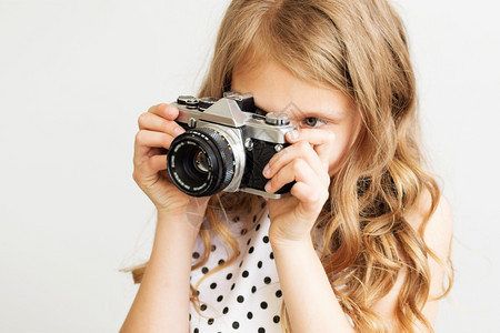 时尚年轻的一个可爱小女孩肖像带着旧SLR摄影机在白色背景下拍摄头发图片