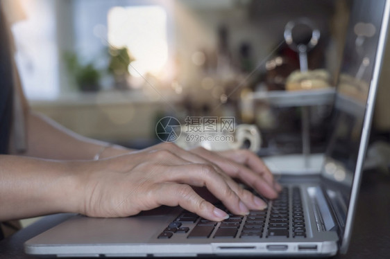 笔记本电脑利用在厨房工作的膝上型计算机键盘笔记本上的女打字在家从事网上业务的新正常生活人概念使用在厨房工作的膝上型计算机数字的重图片
