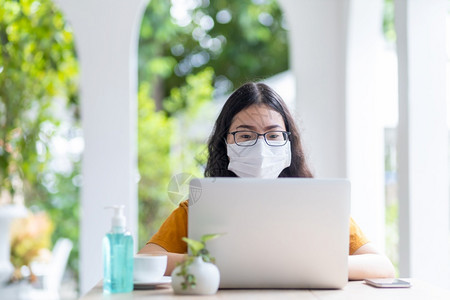 人们互联网在咖啡店用笔记本电脑工作如背景在家工作防止COVID19传播的观念等商业上穿戴保护面罩的女商人自由职业者专的图片