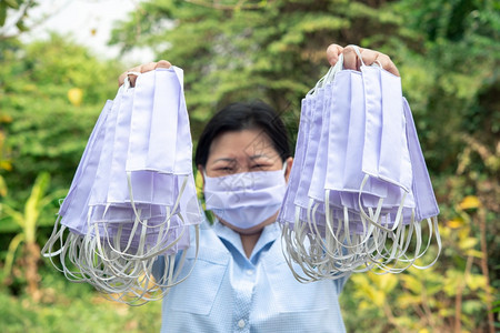 室外手拿防护口罩的女性图片